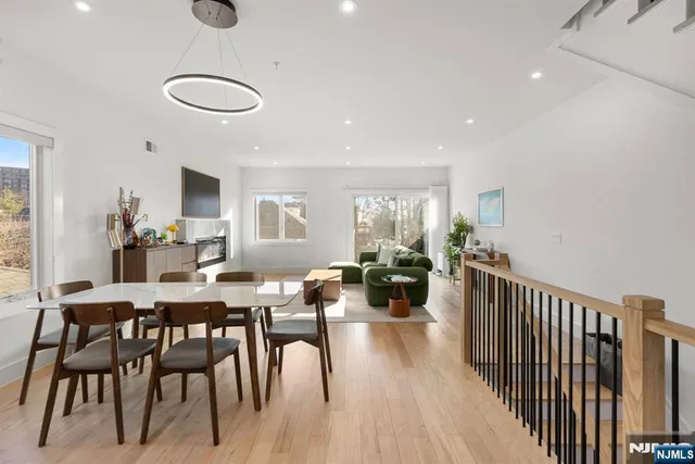 a view of a dining room and livingroom with furniture wooden floor a rug a flat screen tv a painting and a chandelier
