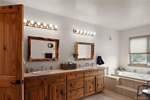 a spacious bathroom with double vanity a mirror and a bathtub