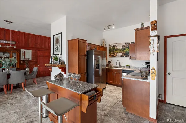 a kitchen with stainless steel appliances granite countertop a refrigerator a stove a sink a dining table and chairs