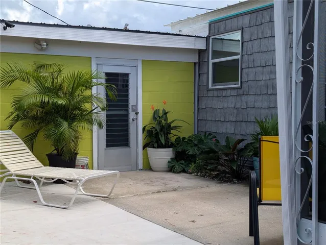 a view of a patio with table and chairs potted plants and large tree