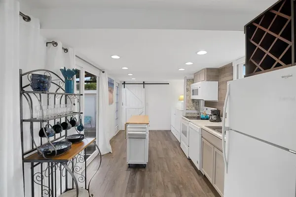 a kitchen with granite countertop a stove a sink a refrigerator and wooden floor