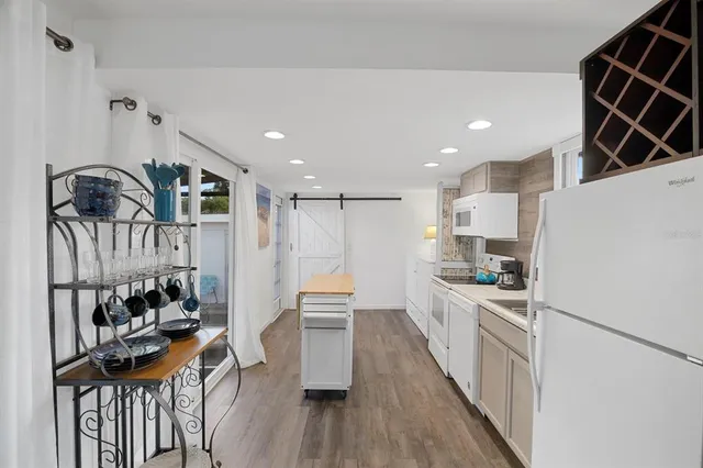 a kitchen with granite countertop a stove a sink a refrigerator and wooden floor