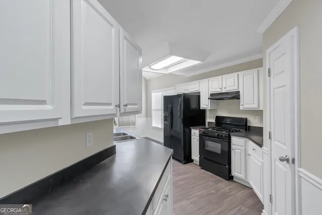 a kitchen with granite countertop white cabinets and stainless steel appliances