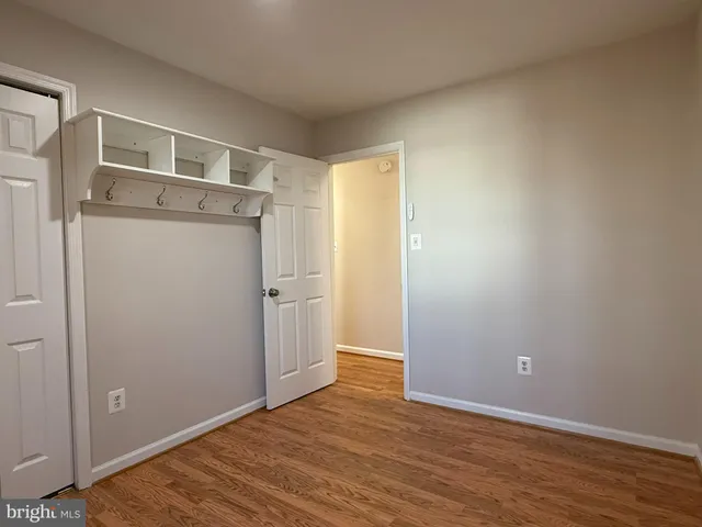 a view of an empty room with wooden floor and closet