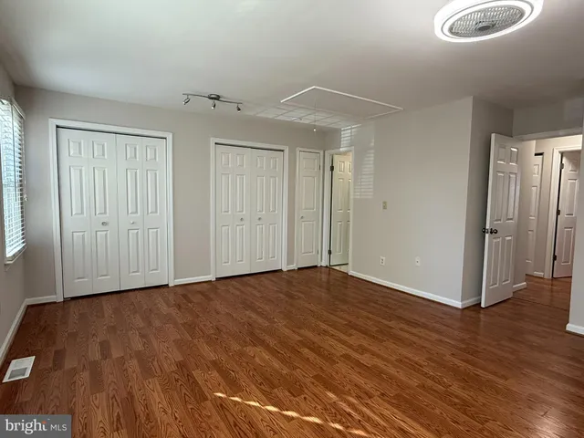 an empty room with wooden floor and a hallway