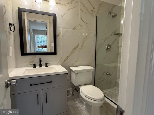 a bathroom with a toilet sink vanity and mirror