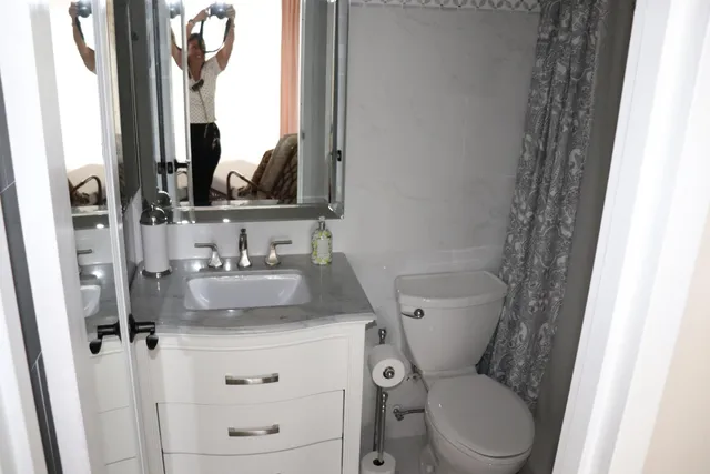 a bathroom with a granite countertop sink toilet and mirror