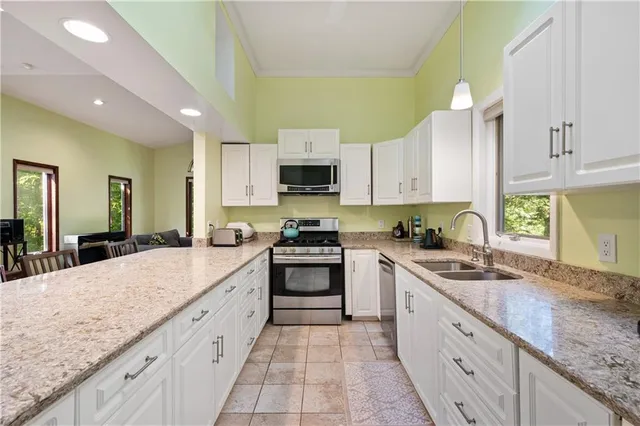 a large kitchen with granite countertop a sink and white cabinets