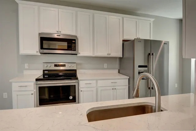 a kitchen with white cabinets and stainless steel appliances