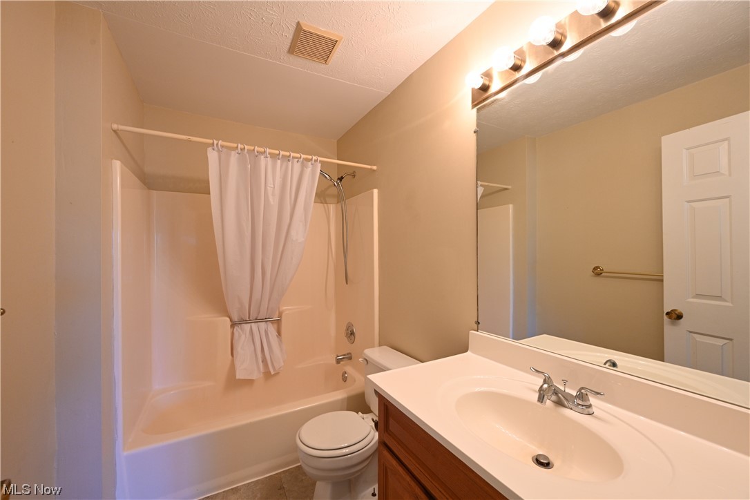28140 Detroit Road, Unit A1 Westlake, OH 44145 - Photo 21 of 30 Full bathroom featuring toilet, a textured ceiling, tile floors, vanity with extensive cabinet space, and shower / bath combo