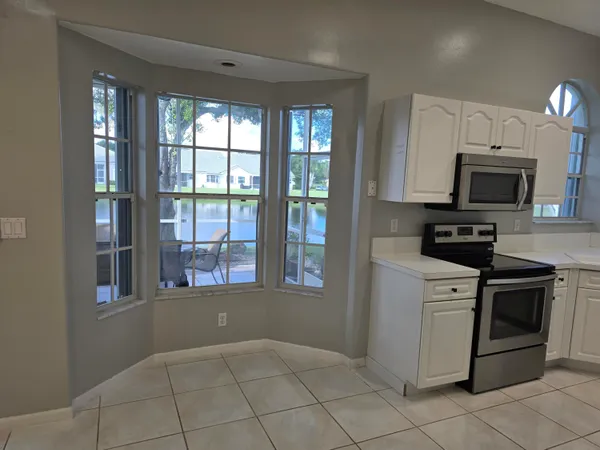 a kitchen with a stove a microwave and white cabinets