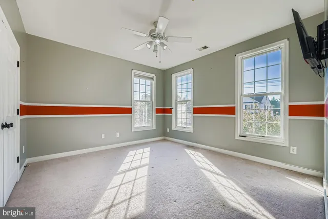 a view of a big room with windows and chandelier fan