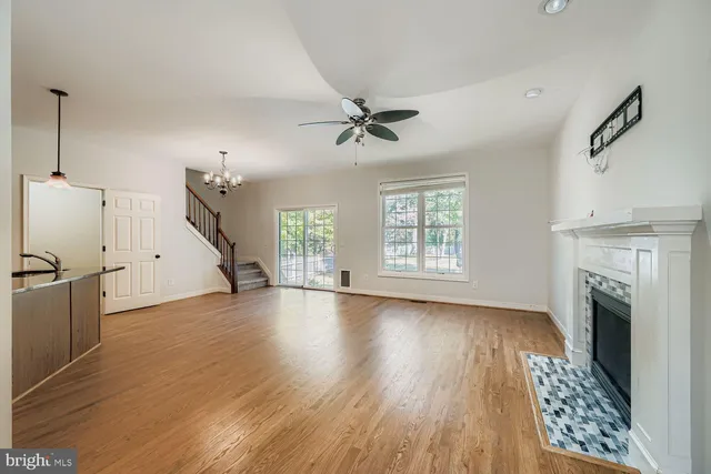 an empty room with windows fireplace and a kitchen view