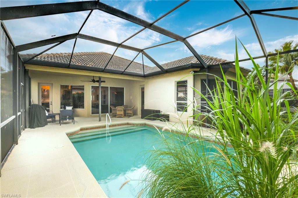 2885 Lone Pine Lane Naples, FL 34119 - Photo 2 of 29 a view of a patio with table and chairs under an umbrella