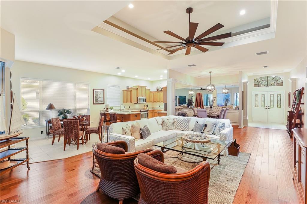 2885 Lone Pine Lane Naples, FL 34119 - Photo 6 of 29 a living room with furniture a wooden floor and a chandelier