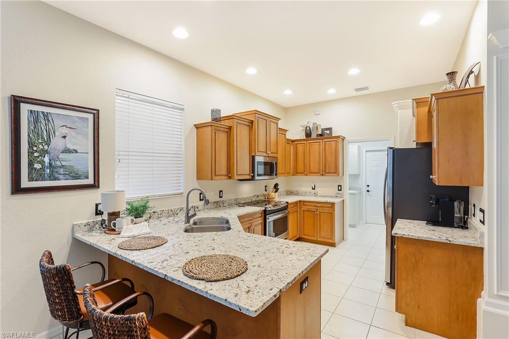 2885 Lone Pine Lane Naples, FL 34119 - Photo 10 of 29 a kitchen with sink refrigerator and stove
