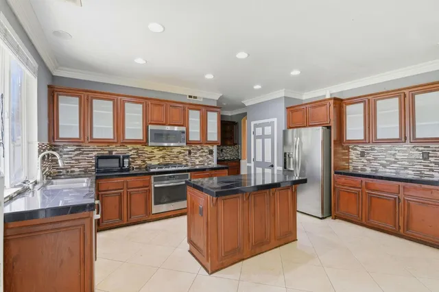 a kitchen with stainless steel appliances granite countertop a sink and a refrigerator
