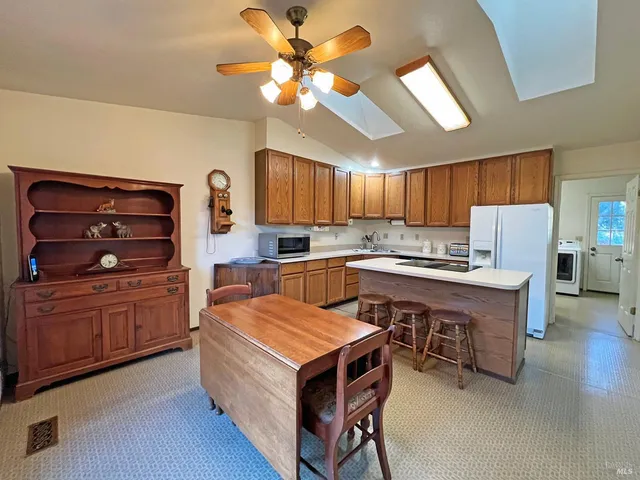 a kitchen with a refrigerator a stove a sink dishwasher and a dining table with wooden floor