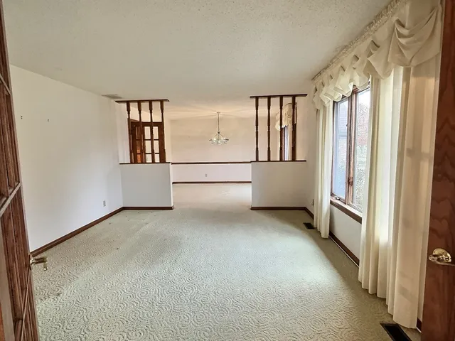 a view of a livingroom with a fireplace a chandelier a wooden table and chairs