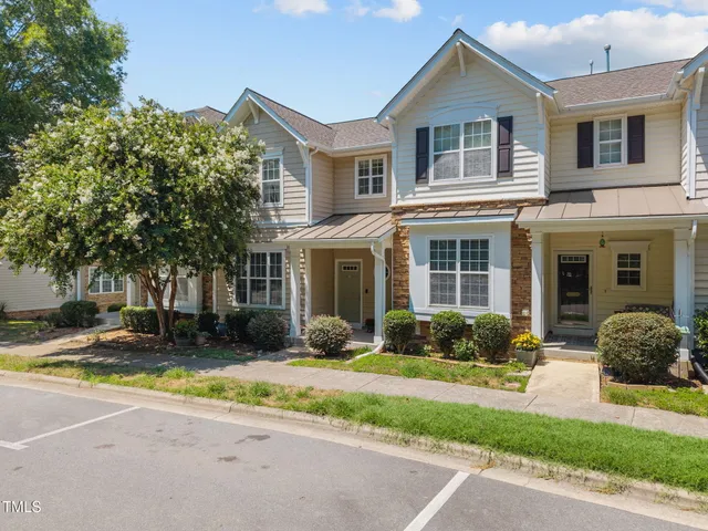 a view of a brick house with a yard and large tree