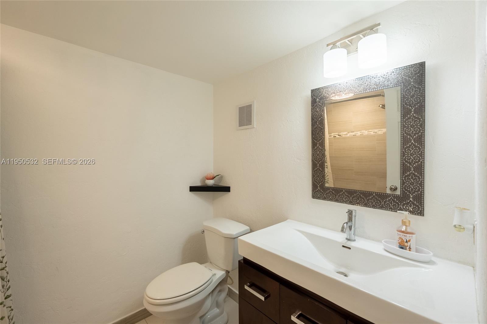 6534 Southwest 114th Place, Unit G75 Miami, FL 33173 - Photo 13 of 52 a bathroom with a sink a toilet a mirror and vanity
