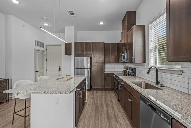 a kitchen with stainless steel appliances granite countertop a sink stove and refrigerator