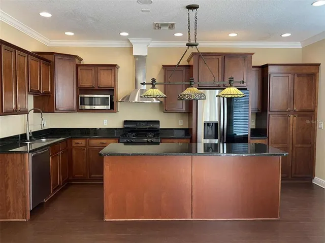 a kitchen with stainless steel appliances granite countertop a refrigerator a oven a sink a stove and a refrigerator