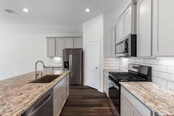 a kitchen with granite countertop a sink and a stove top oven