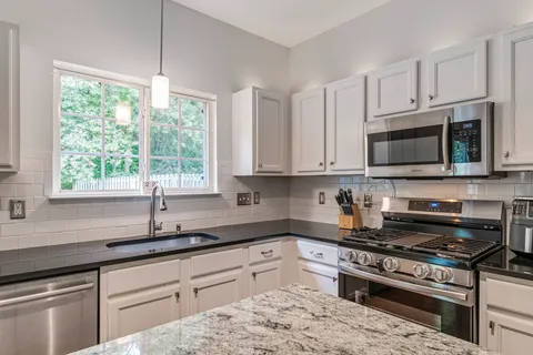 a kitchen with granite countertop a refrigerator stove and sink