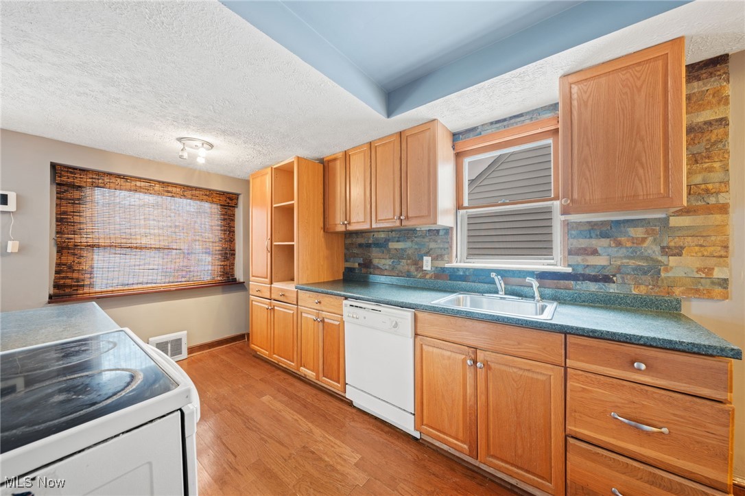 4146 Wyncote Road South Euclid, OH 44121 - Photo 9 of 20 Kitchen with visible vents, white appliances, tasteful backsplash, a sink, and light wood-style floors
