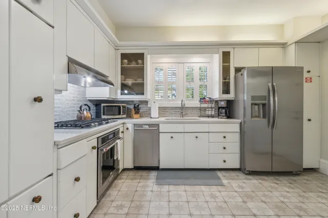 a kitchen with granite countertop a refrigerator stove top oven and sink