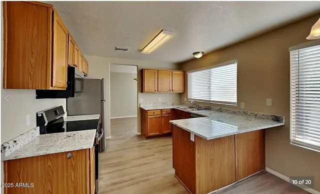a kitchen with granite countertop kitchen island stainless steel appliances a sink stove and a refrigerator