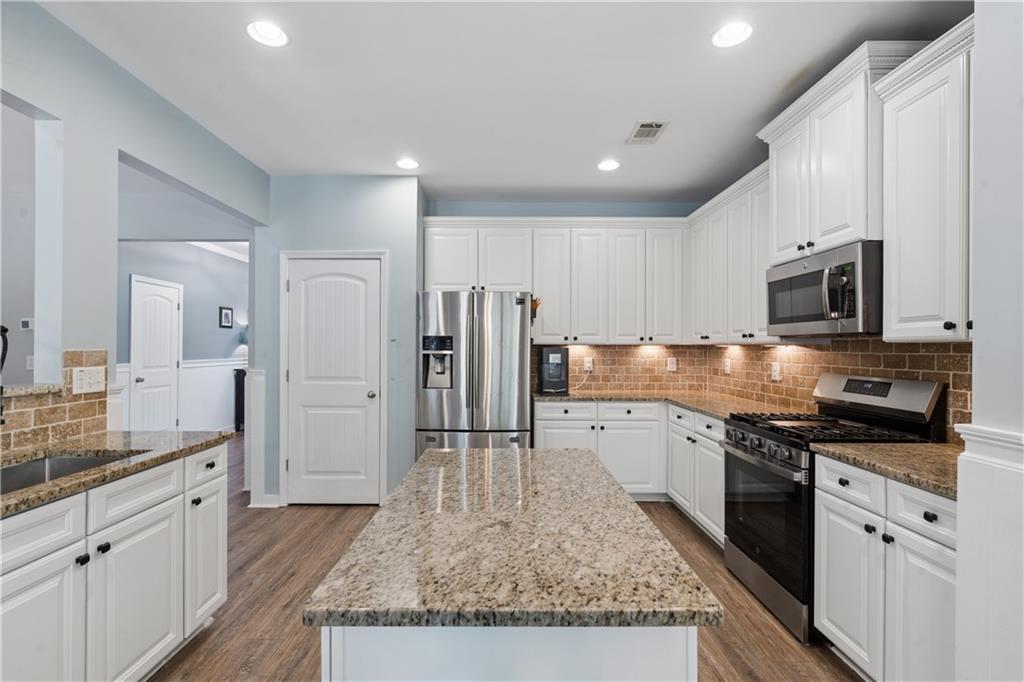 2467 Allsborough Way Dacula, GA 30019 - Photo 14 of 45 a large kitchen with stainless steel appliances granite countertop a lot of counter space and wooden floor
