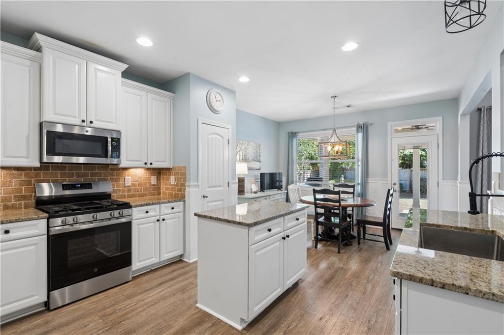 2467 Allsborough Way Dacula, GA 30019 - Photo 15 of 45 a kitchen with stainless steel appliances granite countertop a stove top oven a sink dishwasher and white cabinets with wooden floor