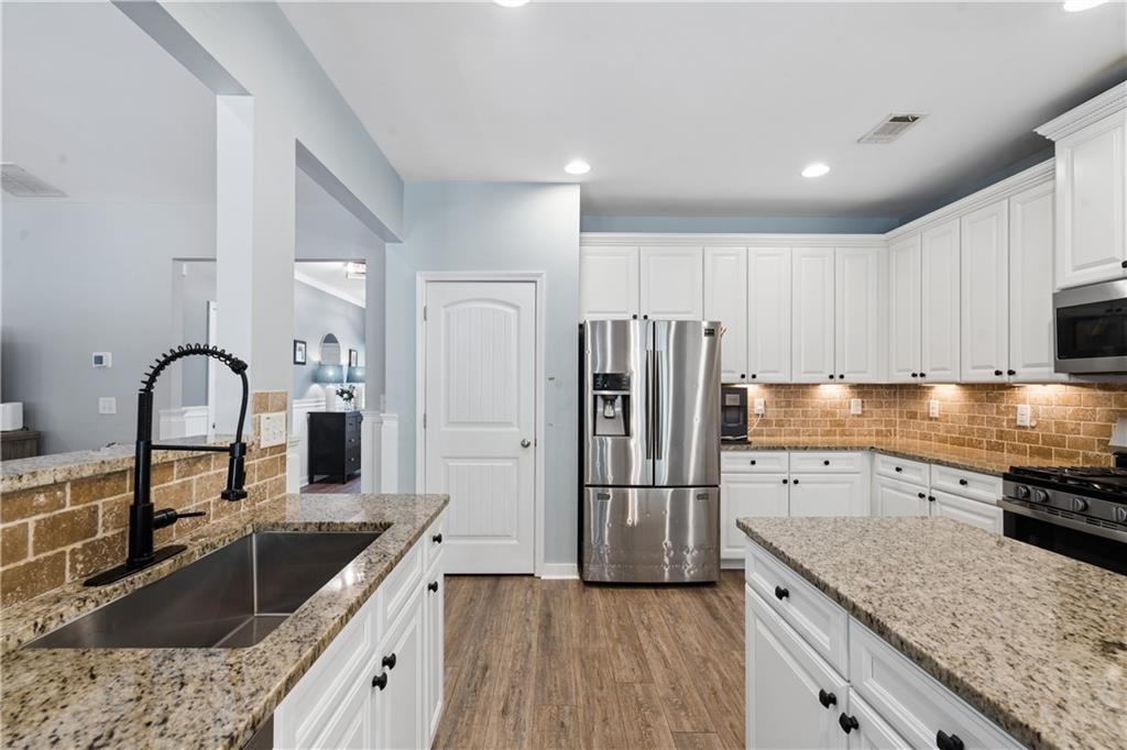 2467 Allsborough Way Dacula, GA 30019 - Photo 21 of 45 a kitchen with granite countertop a sink stainless steel appliances and white cabinets