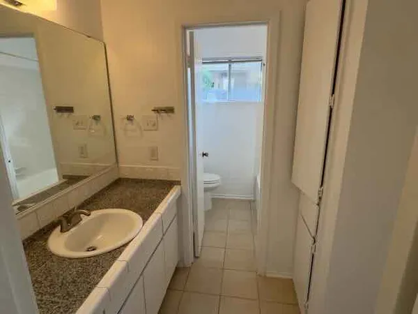 a bathroom with a granite countertop sink a toilet and shower
