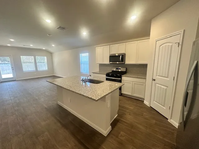 a kitchen with stainless steel appliances a refrigerator a sink a stove a microwave a sink a refrigerator and cabinets