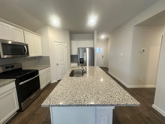 a kitchen with stainless steel appliances granite countertop a sink stove and refrigerator
