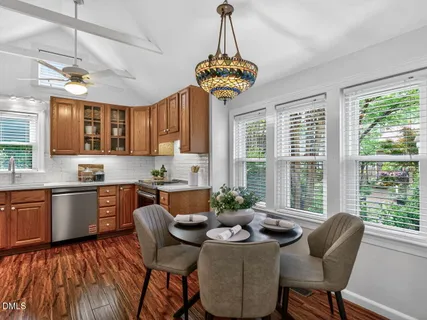 a kitchen with stainless steel appliances granite countertop a stove a sink dishwasher a dining table and chairs with wooden floor