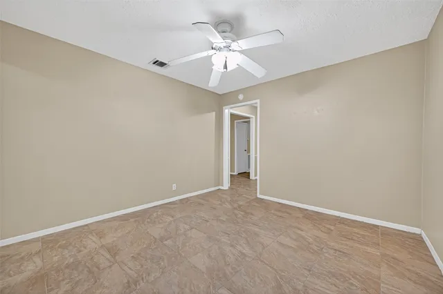 an empty room with a ceiling fan and wooden floor