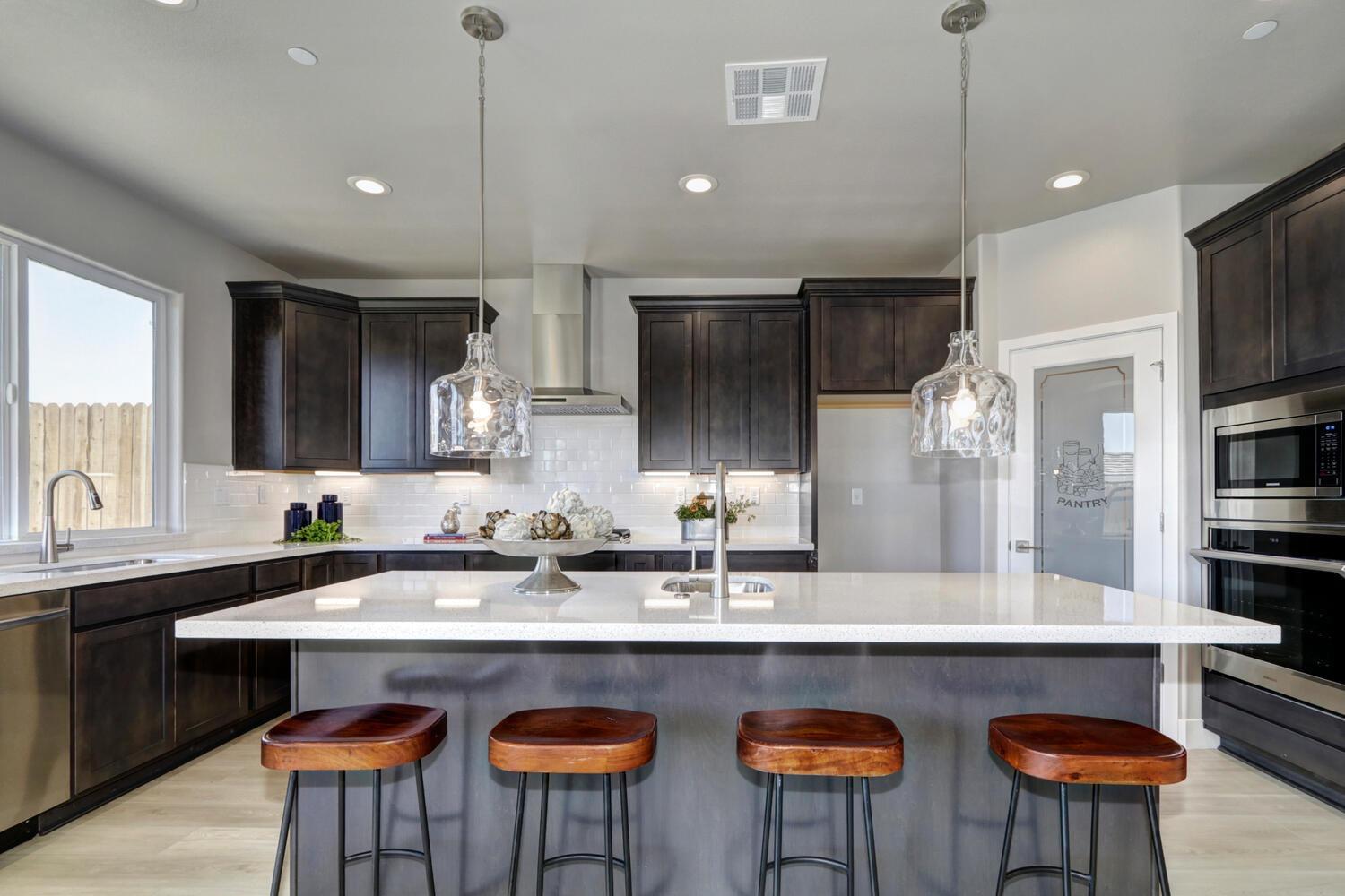 a kitchen with stainless steel appliances granite countertop a sink a stove a kitchen island and chairs