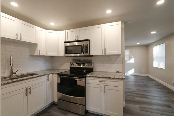 a kitchen with granite countertop white cabinets and stainless steel appliances