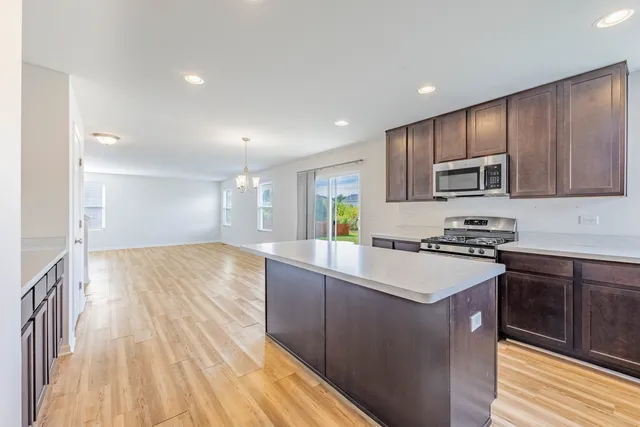 a kitchen with kitchen island granite countertop wooden cabinets and a stove top oven