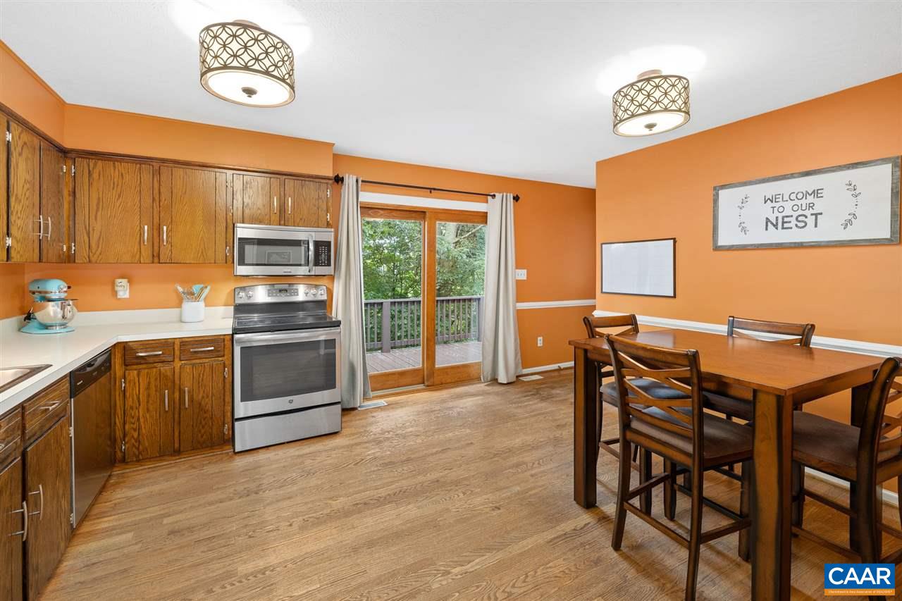949 Chapman Road Stanardsville, VA 22973 - Photo 6 of 41 a kitchen with stainless steel appliances granite countertop a stove a refrigerator a microwave oven with a dining table and chairs with wooden floor