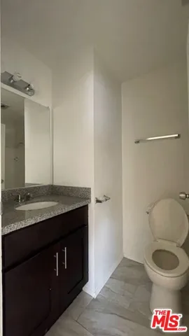 a bathroom with a granite countertop toilet sink and mirror