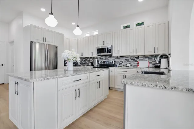 a kitchen with stainless steel appliances white cabinets a sink and a refrigerator