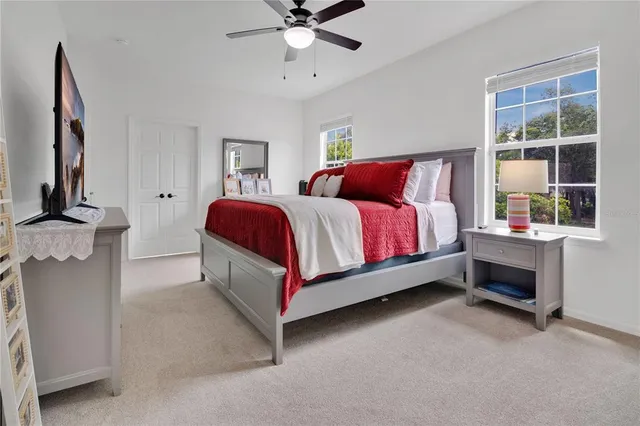 a spacious bedroom with a bed and a flat tv screen on dresser