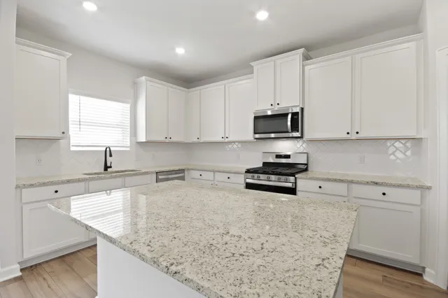 a kitchen with stainless steel appliances granite countertop a sink stove and microwave