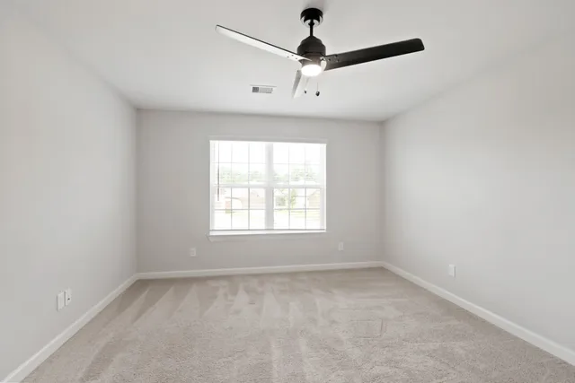an empty room with a window and a fan