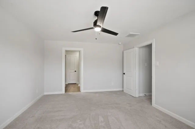 a view of an empty room and chandelier fan